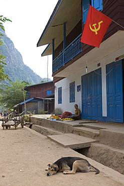 A person and a dog in front of a house at the fishing village Muang Ngoi Kao, Luang Prabang province, Laos