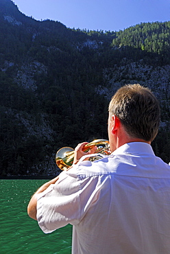 man playing flugelhorn, echo at lake Koenigssee, Berchtesgaden range, National Park Berchtesgaden, Berchtesgaden, Upper Bavaria, Bavaria, Germany