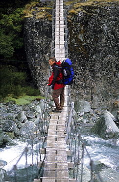 Man on a suspension bridge above the Rees Dart River, Mount Aspiring National Park, South Island, New Zealand, Oceania