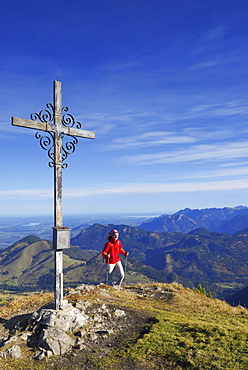 Woman reaching summit cross, Kleiner Traithen, Bavarian foothills, Bavaria, Germany