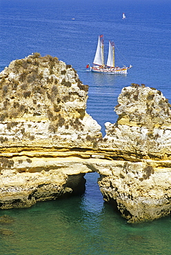 A sailing ship off the rocky coast in the sunlight, Ponta da Piedade, Algarve, Portugal, Europe