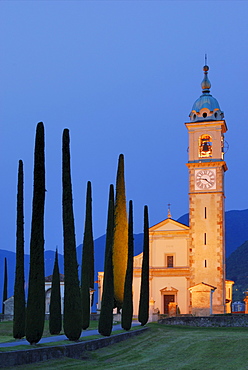 Illuminated church San Abbondino near Gentilino with cypress alley, Gentilino, Lugano, Ticino, Switzerland