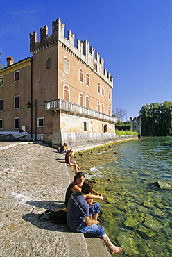 People sitting at the lake at the Scaliger castle, Lazise, Lake Garda, Veneto, Italy, Europe