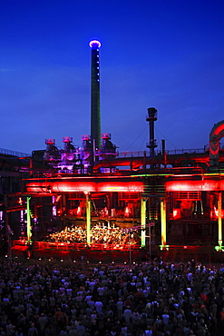 The Duisburg Philharmonic Orchestra playing in front of the illuminated backdrop of the Huette Meiderich, Duisburg, Ruhr Area, North Rhine-Westphalia, Germany, Europe