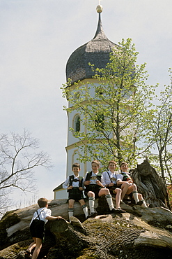 Five boys wearing lederhosen sitting outside a church, Holzhausen, Lake Starnberg, Upper Bavaria, Bavaria, Germany