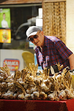 Old man at a stall with garlic bulbs, Provencal market at Buis-les-Baronnies, Haute Provence, Provence, France, Europe