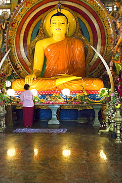 Woman in front of a big Buddha statue in the Gangaramaya temple, Colombo, Sri Lanka, Asia