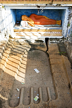 A small Buddha with money offerings in Buddhas foot print, Isurumunjya temple, Isurumuni Maha Vihara, Sacred City, Anuradhapura, Sri Lanka, Asia