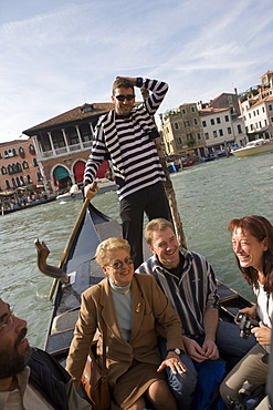 Gondolier on a gondola crossing Grand Canal with passengers, Venice, Veneto, Italy