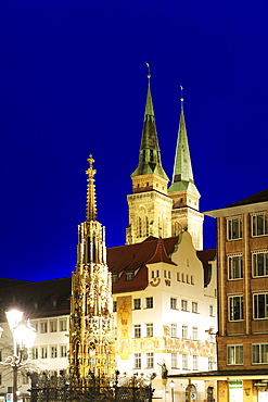 Illuminated fountain Schoener Brunnen on the market square and St. Sebaldus church at night, Nuremberg, Bavaria, Germany