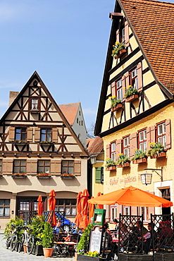 Guests sitting in the beer garden of a restaurant, half-timbered houses, Dinkelbuehl, Bavaria, Germany