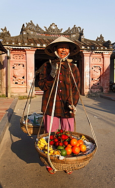 Woman with baskets passing Chua Cau, Japanese Bridge, Hoi An, Annam, Vietnam