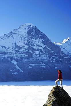 Woman standing on rock and looking towards north face of Eiger above sea of fog, Bussalp, Grindelwald, UNESCO World Heritage Site Swiss Alps Jungfrau - Aletsch, Bernese Oberland, Bern, Switzerland, Europe