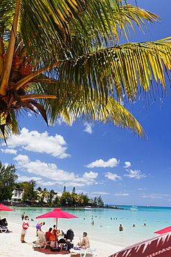 Palm trees and people on the beach in the sunlight, Pereybere, Mauritius, Africa