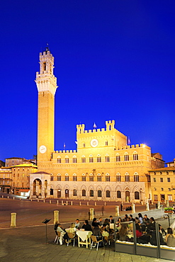 People sitting in a cafe on the illuminated main square Piazza del Campo in Siena with belltower Torre del Mangia in the background, Siena, UNESCO World Heritage Site, Siena, Tuscany, Italy