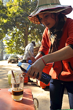 Young Cambodian woman preparing milk coffee near Bayon temple, Angkor Thom, Angkor, Cambodia, Asia