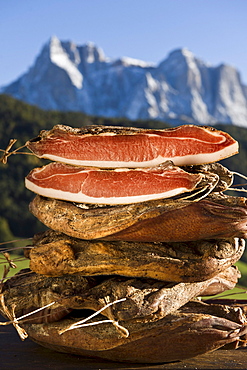 A pile of smoked bacon in front of Schlern mountain range, Kastelruth, Alto Adige, South Tyrol, Italy, Europe