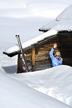 Waving woman in front of an alpine hut in the snow, Alto Adige, South Tyrol, Italy, Europe