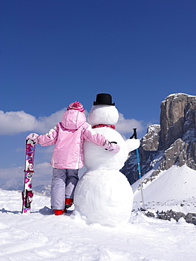 Little girl with skis an snowman, Alto Adige, South Tyrol, Italy, Europe