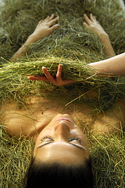 Young woman taking a hay bath, Alto Adige, South Tyrol, Italy, Europe