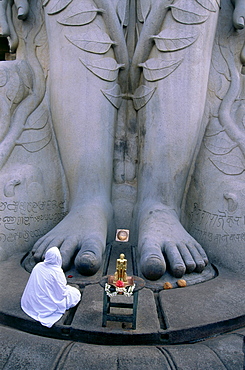 A person cowering in front of the feet of the giant Sri Gometeswara Statue, Sravanabelagola, Karnataka, India