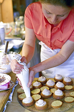 A woman filling muffins at a bakery