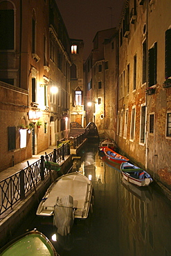 Canal with lights and boats at night in Venice, Italy