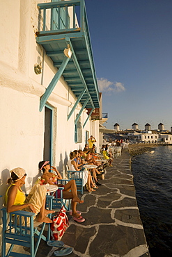 People sitting in Caprice Bar directly at sea, windmills in background, Little Venice, Mykonos-Town, Mykonos, Greece