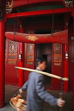 Porter with building material and wooden fish in front of Qiyuan monastery, Jiuhuashan, Anhui province, China, Asia