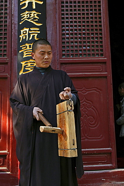 Buddhist Shaolin monk striking a wooden gong, Call for prayer, Shaolin Monastery, known for Shaolin boxing, Taoist Buddhist mountain, Song Shan, Henan province, China