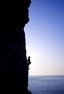 Kalymnos, Greece a woman climbs on a vertical rock pillar above the Aegean Sea, Europe, MR