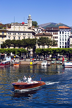 View over Lake Lugano to Luganow with cathedral St. Lorenzo, small motorboat in foreground, Lugano, Ticino, Switzerland