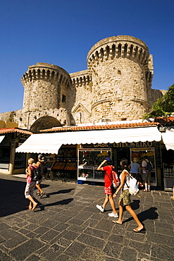 People strolling over Platia Ippokratou with shops, Thalassini Gate in background, Rhodes Town, Rhodes, Greece, (Since 1988 part of the UNESCO World Heritage Site)