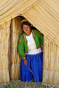 Indigenous woman of the Uros people in front of a reef hut, Lake Titicaca, Peru, South America