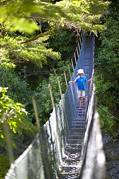 Girl on hanging bridge, rivercrossing in Abel Tasman National Park, north coast of South Island, New Zealand