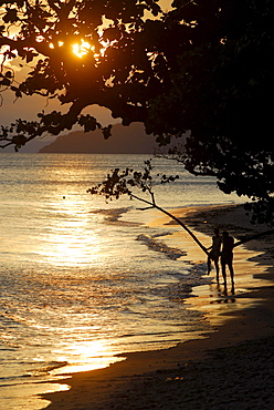 Couple taking pictures on Hat Phra Nang beach at sunset, Krabi, Thailand