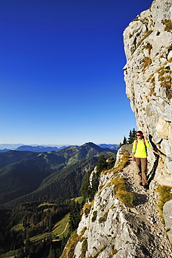 Woman walking on an exposed trail at a rockface, Brunnstein, Bavarian Prealps, Upper Bavaria, Bavaria, Germany