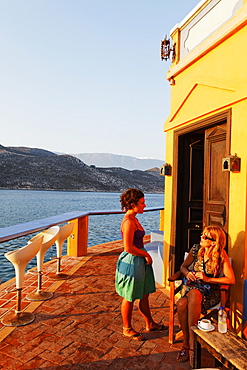 People outside of Faros-Coupa bar in the evening sun, Kastelorizo Megiste, Dodecanese Islands, Greece, Europe