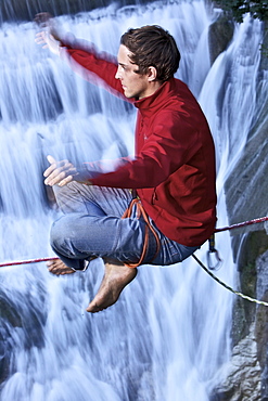 Young man balancing on a highline over a stream, Fuessen, Bavaria, Germany, Europe