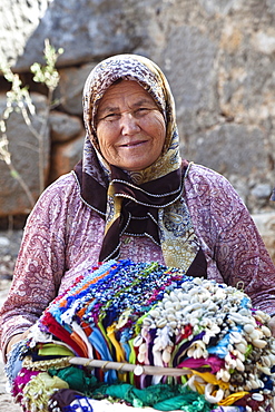 Old turkish woman selling souvenirs at Kalekoy castle, Simena, lycian coast, Mediterranean Sea, Turkey