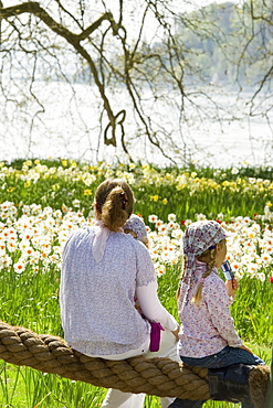 Flower meadow with daffodils and woman with a children, Mainau Island, Lake Constance, Baden-Wuerttemberg, Germany, Europe