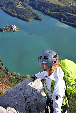 Young woman at fixed rope route Rino Pisetta looking to Lago die Toblino, Sarche, Calavino, Trentino, Trentino-Alto Adige, Suedtirol, Italy