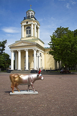 Cow sculpture Cow of Golden Sun and Silver Moon by artist Helena Heinrihsone is part of the Ventspils CowParade art project and situated on the town hall square by St. Nicholas Lutheran church, Ventspils, Latvia, Baltic States, Europe