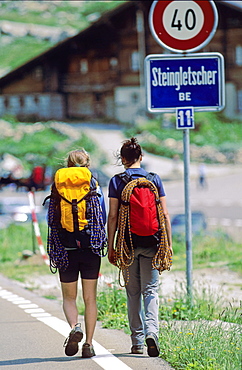 Two young women with climbing equipment walking along street, Bernese Oberland, Canton Bern, Switzerland