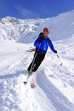 Young man downhill skiing from Wildspitze on glacier, Oetztal Alps, Tyrol, Austria