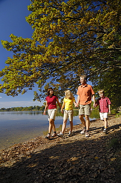 Family walking along the lake shore of Lake Saffelsee, Upper bavaria, Bavaria, Germany