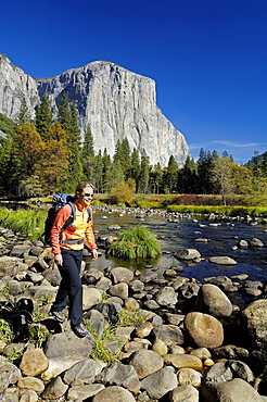 Woman wearing rucksack hiking on stony brookside, Yosemite National Park, California, North America, America