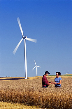 Couple in Wheat Field near Wind Turbine, St. Leon, Manitoba