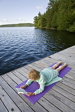 Woman reading on cottage dock, Smoke Lake, Algonquin Park, Ontario