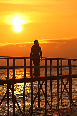 Woman strolling on wooden pier at sunrise, Lake Winnipeg, Matlock, Manitoba